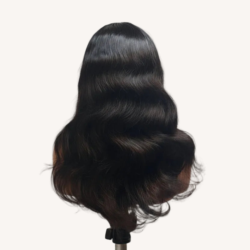 Black hair extensions on a mannequin head against a plain background